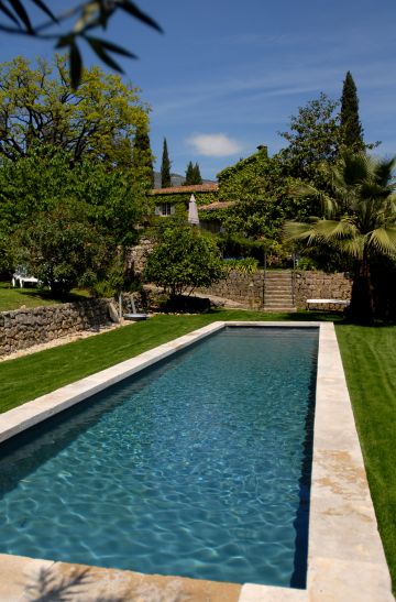 With a few scattered paving stones echoing the stone border, this traditional lap pool is extraordinarily elegant and conjures images of a painting in myriad shades of green.