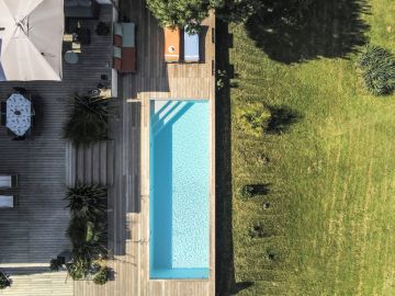 Depuis les airs, la piscine s'allonge entre la maison et le jardin et nous montre toute sa longueur.