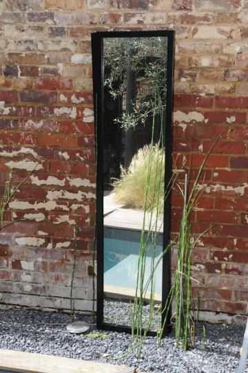 Installé directement contre le mur d'enceinte en brique, un miroir reflète la Piscinelle iki et donne une perspective agréable à l’œil dans cette petite cour intérieure.