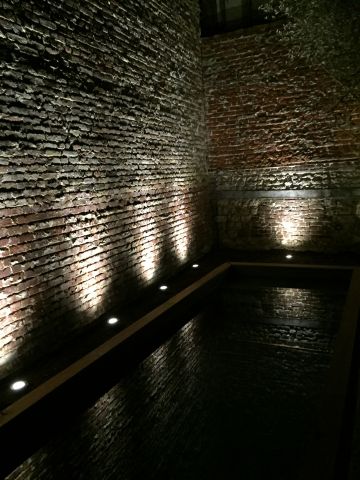 A la nuit tombée, les murs de brique qui entourent la piscine prennent une dimension mythique éclairés depuis le sol et permettent des reflets féeriques sur le plan d'eau.