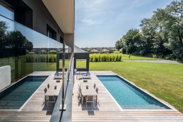 La piscine se reflète dans le garde-corps vitré de l'étage de cette maison moderne au cœur du Brabant Wallon pour créer une image déroutante.