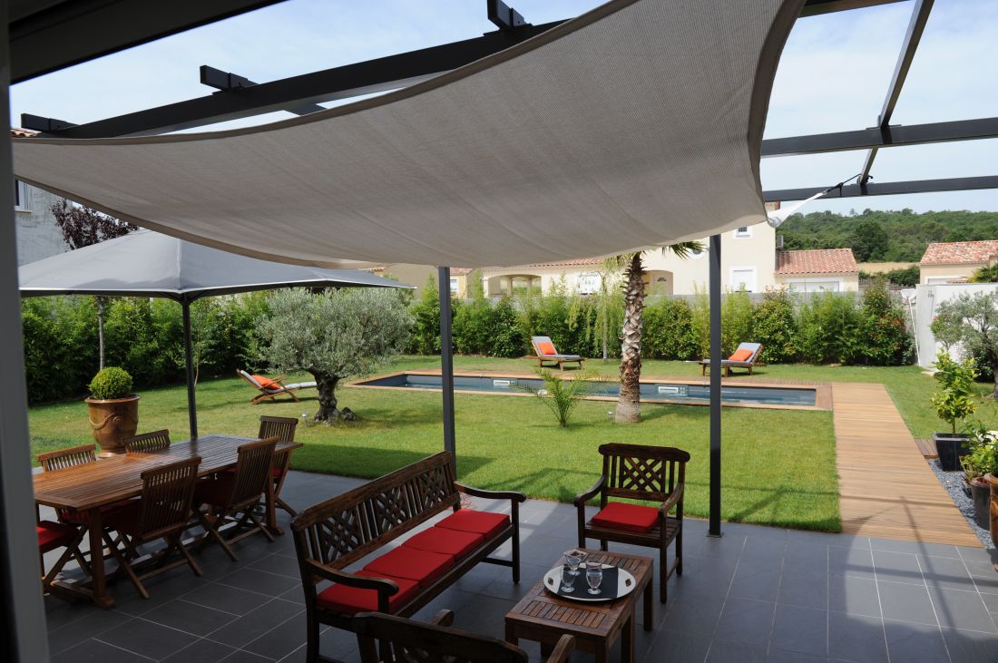 Designer lap pool with olive tree and tiled patio.