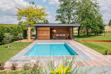 Une grande Piscinelle avec liner gris clair, margelle en pierre bleue et un beau pool house en Belgique.