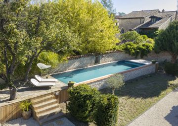 Piscine hors-sol de 12m x 3,5m avec un habillage traditionnel en pierres sèches.