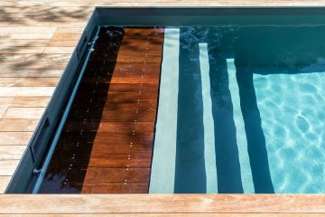 Folded away beneath the top step of the submerged tanning ledge, the pool's slatted safety cover is as discreet as it is effective.