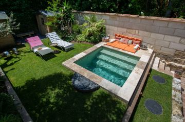 Avec une simple margelle en pierre naturelle et une petite plage pour s'allonger, l'espace piscine est à la fois réduit à sa plus simple expression et laisse en même temps au reste du jardin sa juste place de respiration.