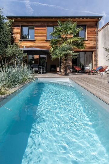 La piscine paysagée est le tapis bleu du jardin luxuriant.