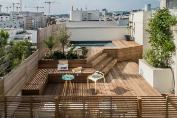 Les banquettes réalisées dans le même bois que celui de la terrasse apportent design et sobriété au salon d'extérieur, un véritable prolongement de l'esprit de cette Piscinelle.