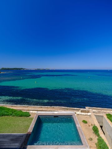 Vue depuis l'étage : la parcelle descend vers la baie et le bassin vient s'inscrire dans la dernière terrasse avant les galets.
