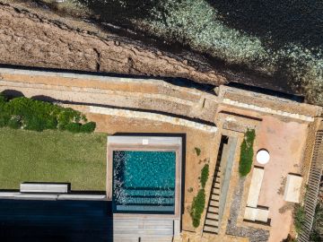 La pelouse, le muret de pierre, la roche brune, l'eau claire du bord : quatre matières qui se succèdent sans transition inutile.