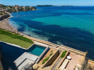 Le terrain finit dans la baie. Entre le carré d'eau et la mer ouverte, un muret de pierre, une langue de galets, puis la ligne des îles.