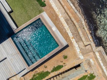 Les gradins de pierre descendent vers le rivage ; le bassin reste en haut, à hauteur de terrasse, à hauteur de corps.