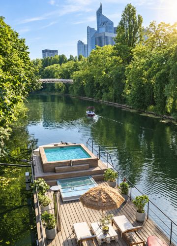 Une Piscinelle installée hors-sol sur une péniche amarrée à Neuilly, sur la Seine, avec une vue sur les tours de la Défense.