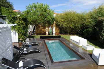 Une petite Piscine couloir de nage modèle Iki (sans autorisation administratif) avec une terrasse dans un jardin