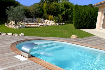 Une piscine arrondie avec une terrasse et lame d'eau