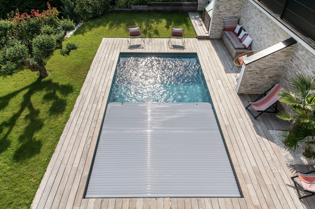 Couverture automatique de piscine de sécurité immergée sous banquette en cours d'ouverture