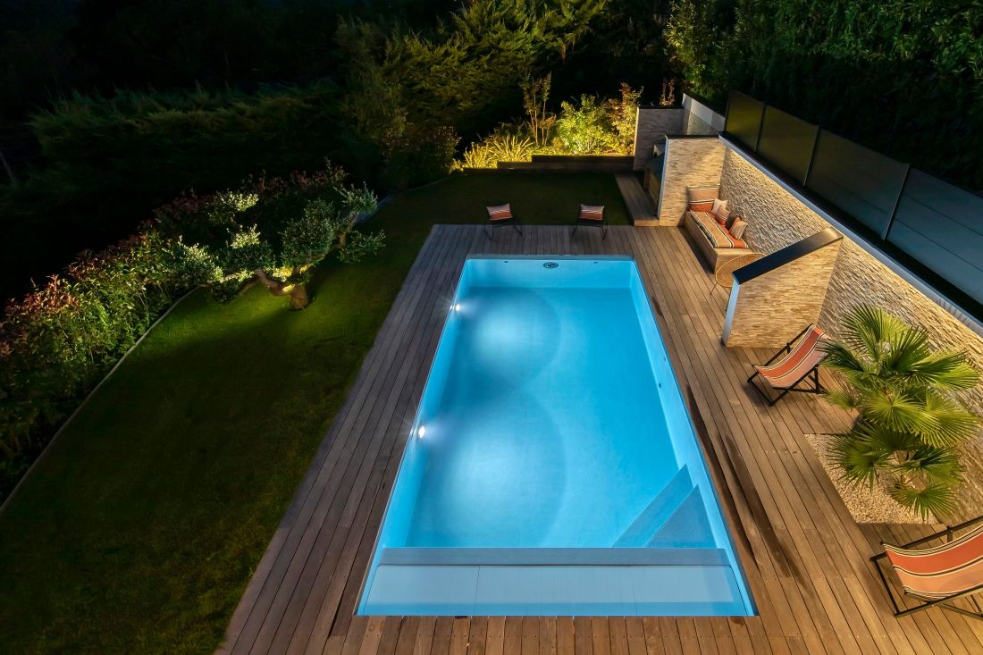 L'espace piscine est intégré à un écrin de verdure dont les éclairages nocturnes rendent le bassin aussi accueillant de jour que de nuit.