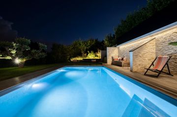 A brighter reflection of a sky turned navy blue, the pool connects interior and exterior, day and night, as an interface that both separates and unites.
