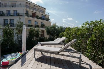 Depuis la terrasse en ipé au bord de la piscine les bain de soleil donnent une vue sur les immeubles environnant pour composer un décor surréaliste.