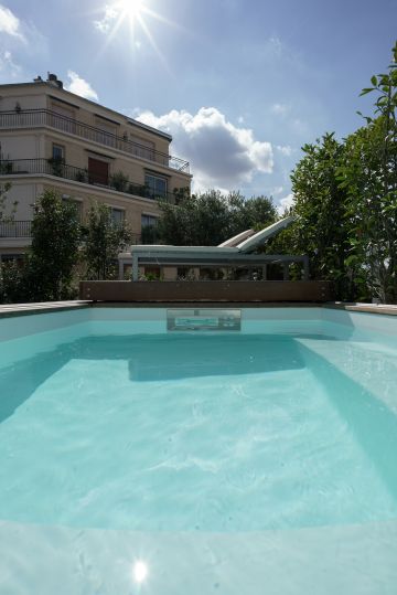 Sous un soleil radieux, une Piscinelle et son Rolling-Deck parfaitement intégrés à ce toit-terrasse font le bonheur de leurs propriétaires.