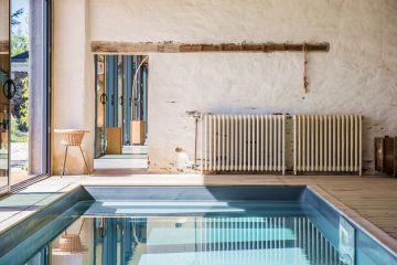 The pool's slate-grey liner contrasts with the colours and aged look of the wall and decorative items.