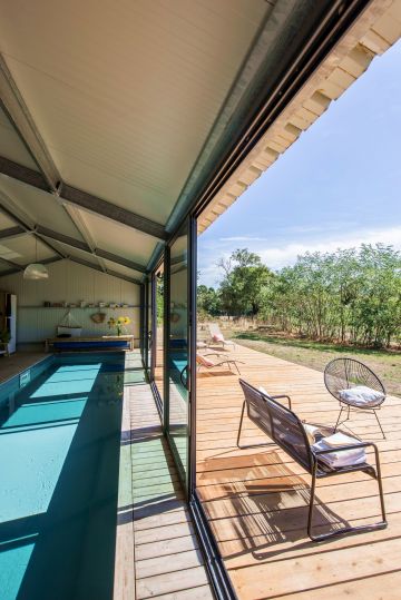 In and out. Une fois les bais vitrées ouverte, cette piscine semble à la fois être une piscine d'intérieur et d'extérieur grâce au prolongement de la terrasse réalisée dans les mêmes matériaux.