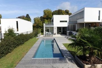 Une piscine couloir de nage Cn10 avec une terrasse devant une maison design