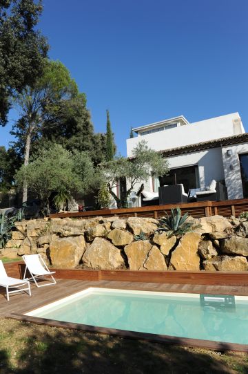 Une piscine de charme au pied d'un maison d'architecte et d'un bel enrochement naturel.