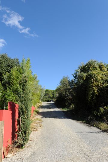 La propriété est ceinte d'un grand mur ocre rouge et borde une petite route provençale.