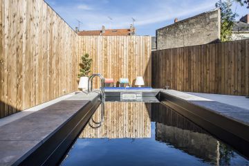 Une large plage une pierre, un MF5 Piscinelle et une échelle en inox, une cour bétonnée et une palissage en bois clair... un mélange des matières pour aboutir à une réalisation à l'identité unique.