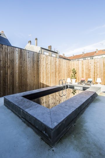 Le liner noir de la piscine agit comme un miroir qui reflète l'ensemble du décor environnent.