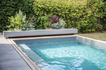 La piscine fait comme une passerelle liquide entre la terrasse en céramique et le gazon du jardin.