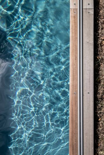 Le rail qui permet de dérouler le Coverseal® est fixé sur la margelle en bois de la piscine.