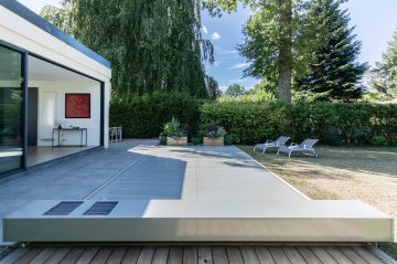 Une fois fermée, la couleur de la couverture rappelle celle de la terrasse et masque avec sobriété la piscine qui sait alors se faire oublier.