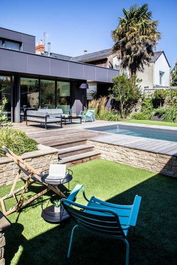 Piscine semi-enterrée rhabillée d'un mur en pierre sèche et d'une terrasse en ipé près de Nantes.