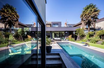 La piscine se reflète dans les baies vitrées de l'annexe de la maison pour une image surprenante de modernité.