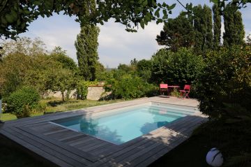 L'espace piscine est sur une terrasse dominant le verger plus bas et les champs au loin.