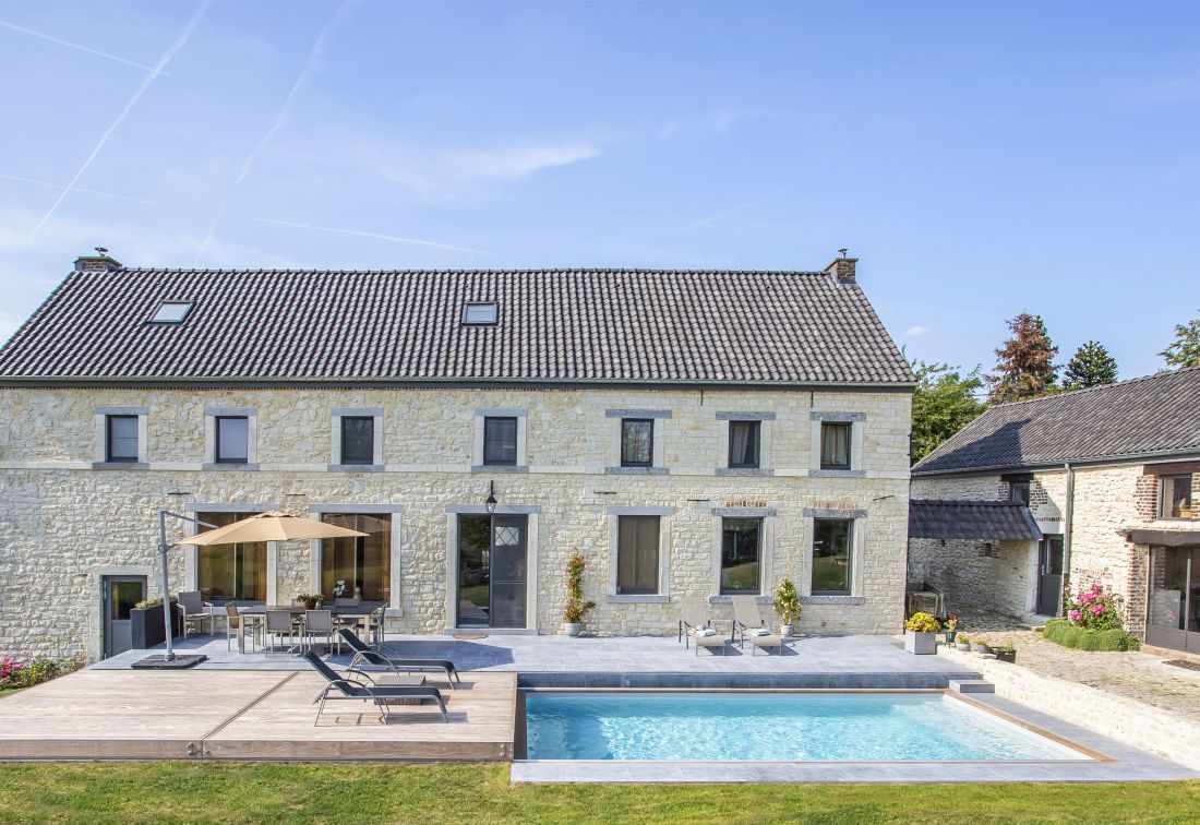 Une grande piscine auprès d'une grande bâtisse traditionnelle.