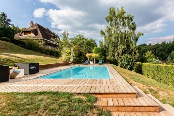 Un escalier réalisé sur-mesure permet de lier la terrasse de la piscine au niveau inférieur du jardin tout en conservant une cohérence dans les matériaux utilisés.