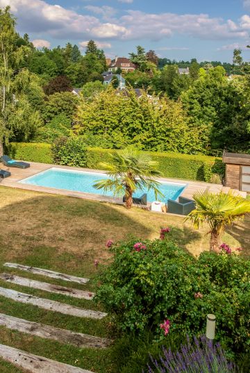 La piscine est implantée sur une terrasse en contrebas de la maison dans ce terrain en pente proche de Bruxelles.