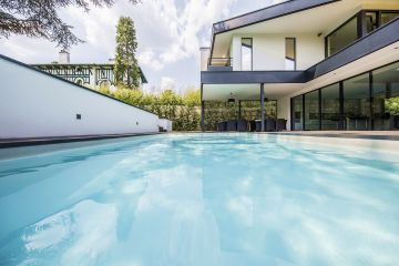 A calm, gently shimmering expanse of water highlights the modernism of the house.