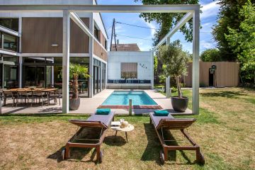 Le bardage bois verticale de la maison confère une modernité à l'espace piscine.