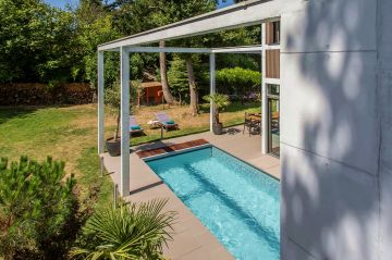 Aux heures d'été, entre un jardin ensoleillé et la fraîcheur de la maison se trouve une piscine atypique et accueillante.