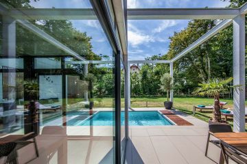 The pool surface is reflected in the living room patio door and the overhead structure gives this project its unique, characteristic sense of volume.