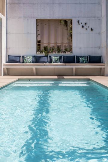 This stylishly designed pool area has a weathered look that could be described as a minimalist, almost brutalist type of luxury, with its unapologetic use of exposed concrete.