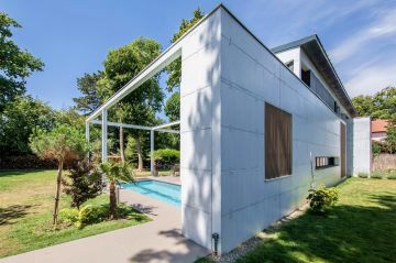 The vertical shutters on the white wall with its window echo the cladding on the house, a design that resonates with decorative features surrounding the pool.