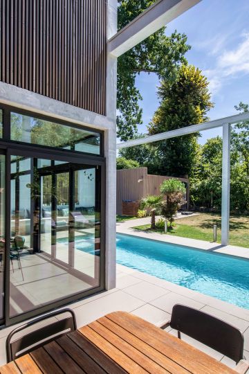 La structure de béton blanc semble matérialiser les murs de cette pièce extérieure que représente ici cet espace piscine atypique.