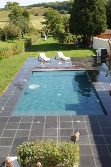 Une piscine Piscinelle installée en pleine campagne et entourée d'un beau dallage granité.