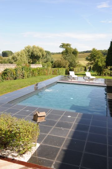 Une piscine Piscinelle installée en pleine campagne et entourée d'un beau dallage granité.