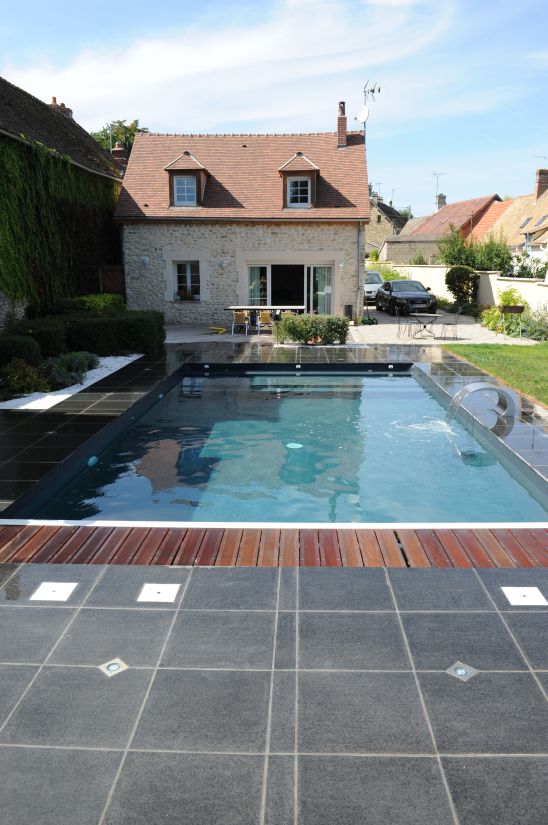 The pool is positioned in front of the stone-built house like a large mirror.